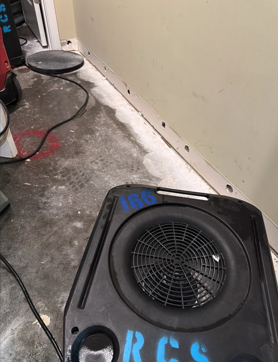 Air mover drying an exposed concrete slab in a Louisville basement after water damage