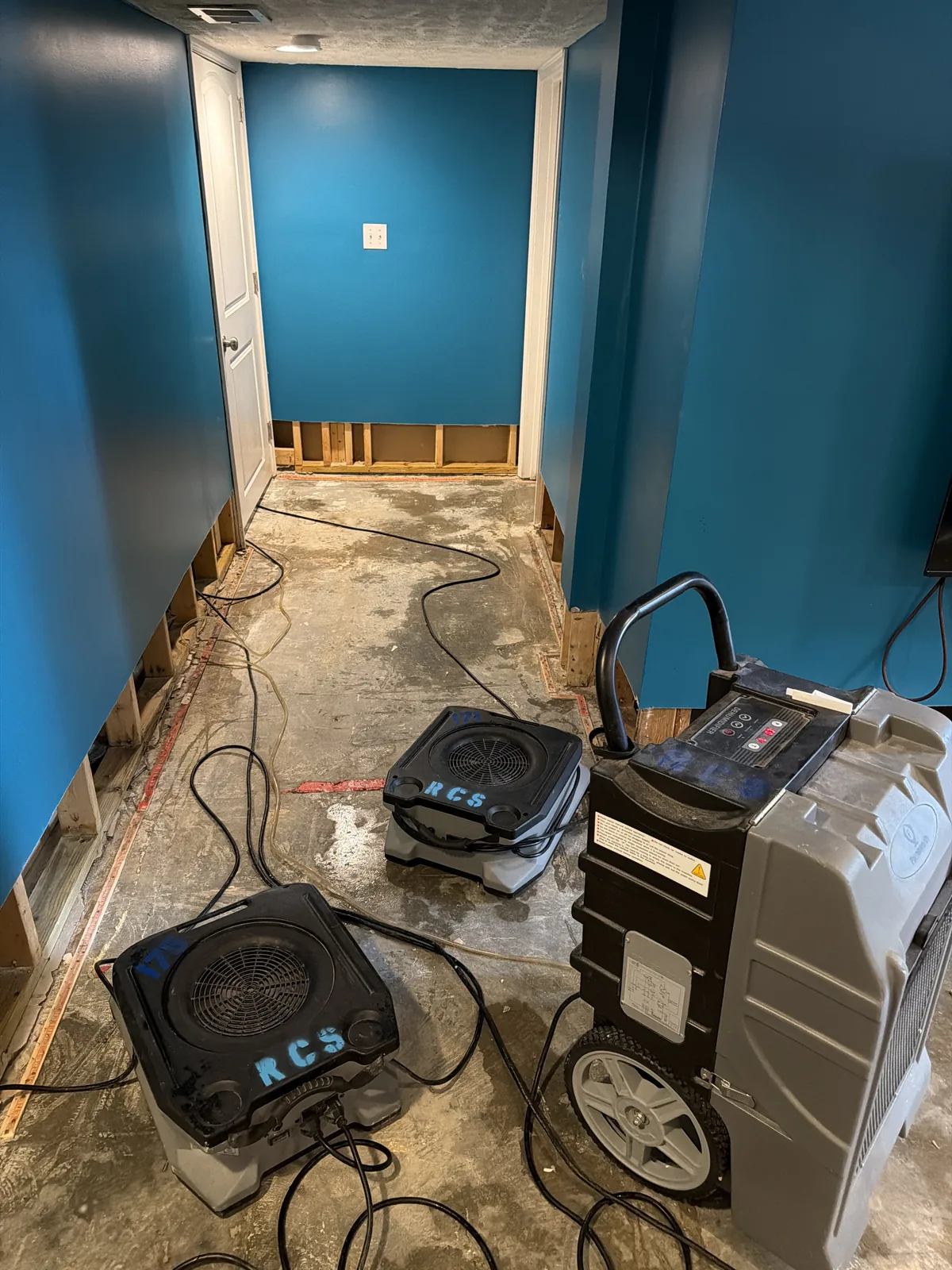 Air movers and a dehumidifier drying a water-damaged room in Louisville KY