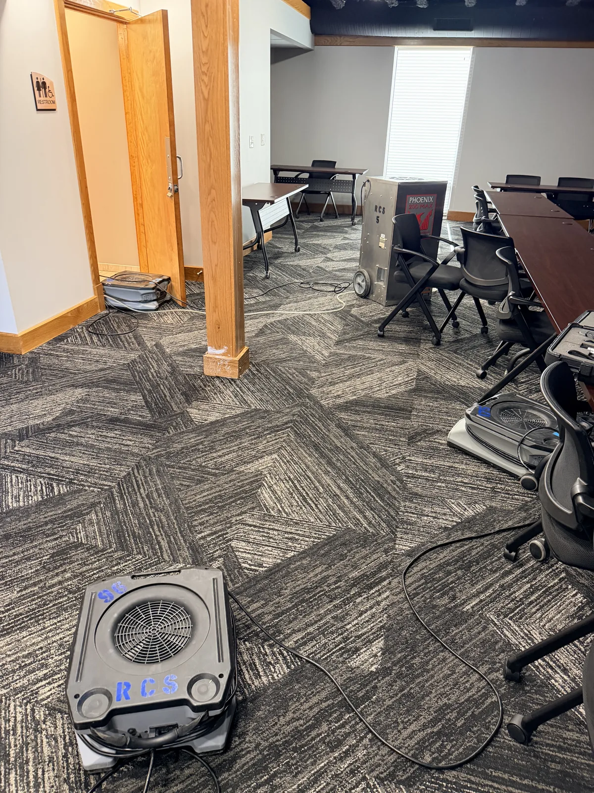 Air mover drying water-damaged carpet in a Louisville commercial office during restoration