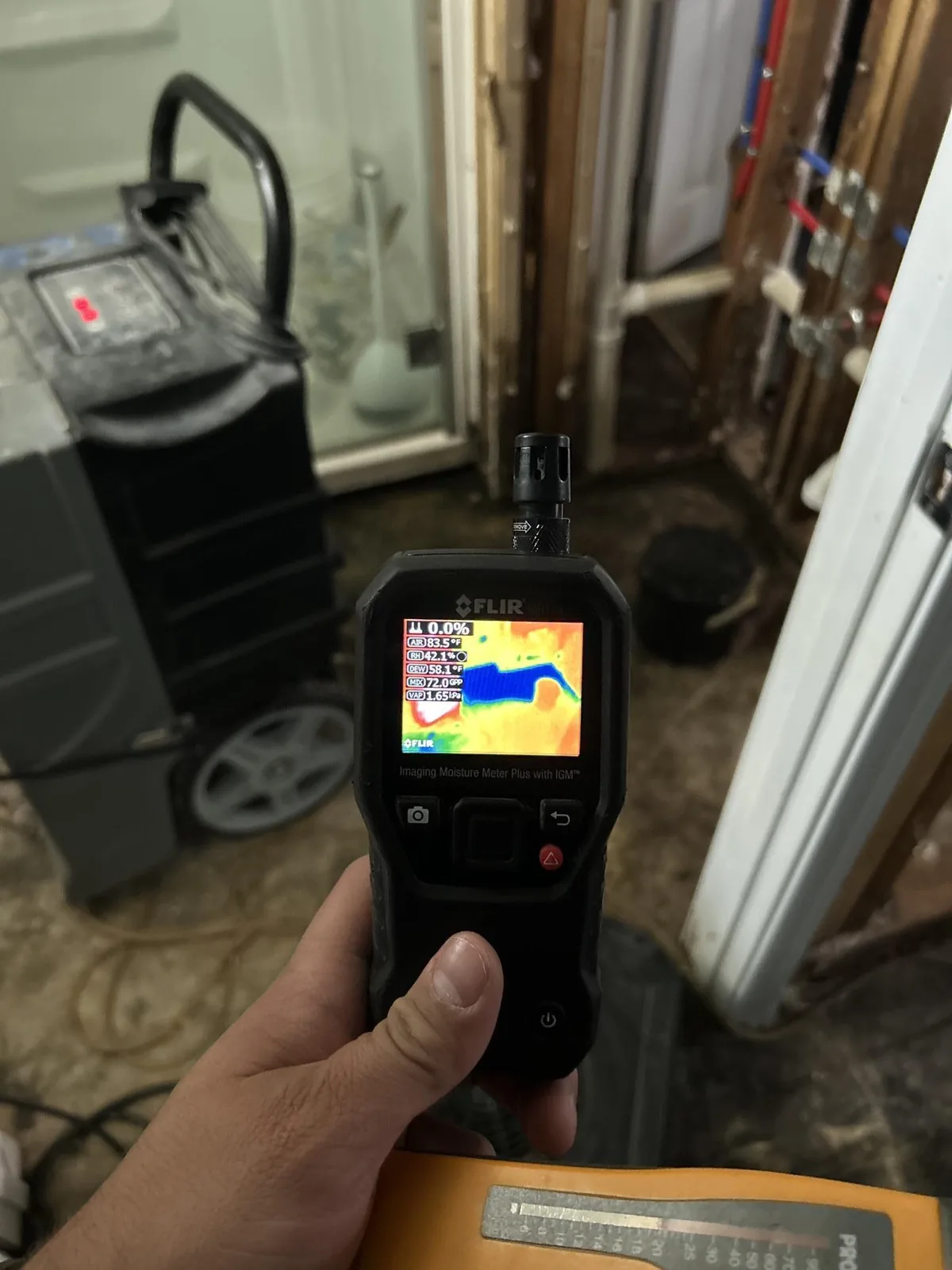 Technician using a thermal imaging camera to find hidden moisture during a Louisville water damage inspection